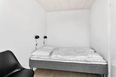 a bed in a white room with a black chair at 792-Thisted-Havstokken-22-1 in Thisted