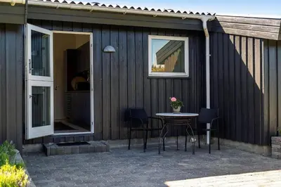 a patio with a table and chairs and a building at 1013-Thisted-Sine-Krokones-Vej-12 in Torsted