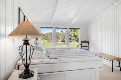 a white bedroom with a bed and a lamp at 1013-Thisted-Sine-Krokones-Vej-12 in Torsted