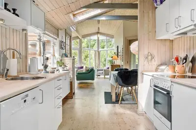 a kitchen with white cabinets and a living room at 704-Thisted-Kristinesvej-54 in Thisted