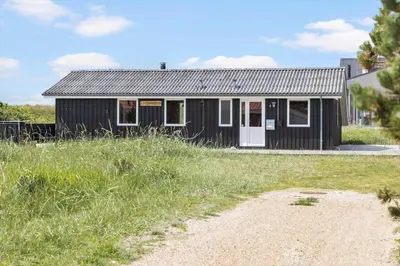 a black house with a white door in a field at 525-Vestervig-Spovevej-5 in Vestervig