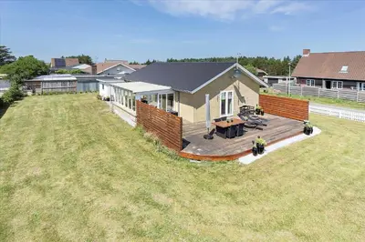 a large yard with a house with a wooden deck at 110-Vestervig-Svanholmvej-10 in Vestervig