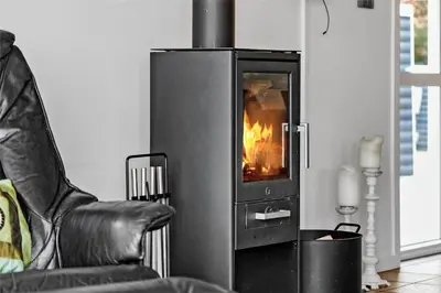 a fire oven in a living room with a chair at 433-Thisted-Tunvej-20 in Thisted