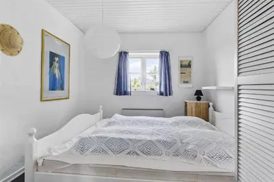 a white bedroom with a white bed with blue curtains at 643-Thisted-Bredkaervej-69-A in Thisted