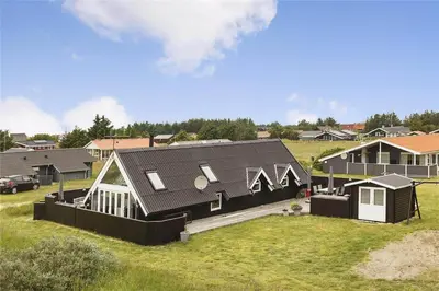 a house with a black roof in a field at 513-Thisted-Fiskervej-159 in Thisted