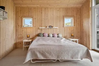 a bedroom with a bed with two tables and two windows at 140-Vestervig-Bekkasinvej-14 in Vestervig