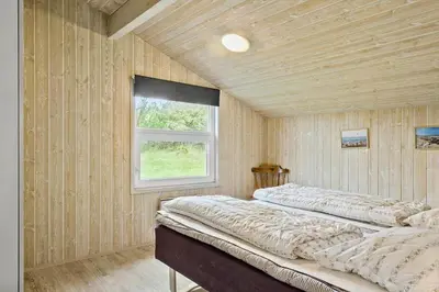 two beds in a room with wooden walls and a window at 970-Thisted-Klitstien-47 in Torsted
