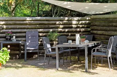 a group of tables and chairs in front of a wooden wall at 216-Snedsted-Grahavrevej-6 in Snedsted