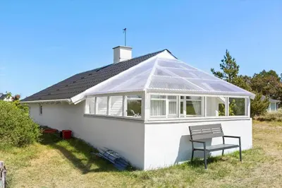 a white house with a conservatory with a bench at 314-Thisted-Mose-Bollevej-14 in Thisted