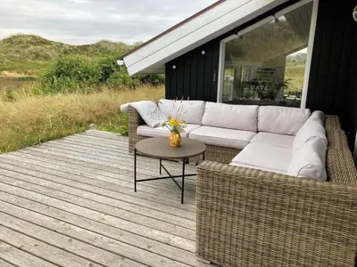 a patio with a couch and a table on a deck at 962-Thisted-Bavnbak-27 in Torsted