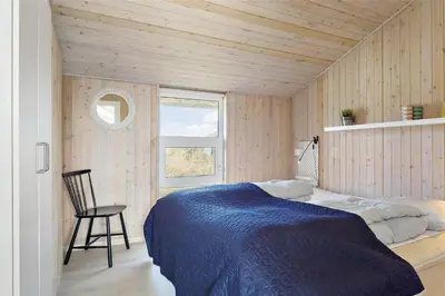 a bedroom with a bed and a chair and a window at 662-Thisted-Havbovej-18 in Thisted