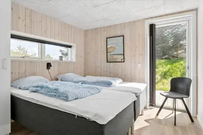 two beds in a room with a chair and a window at 171-Thisted-Molgaardsvej-71 in Thisted