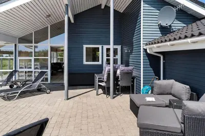 a blue house with a patio with a table and chairs at 950-Thisted-Mombak-1 in Torsted