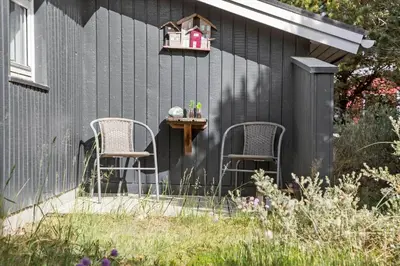 a black house with two chairs and a table at 589-Thisted-Klitrosevej-3 in Thisted