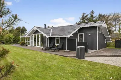 a small grey house with a deck in a yard at 435-Vestervig-Sivsangervej-32 in Vestervig
