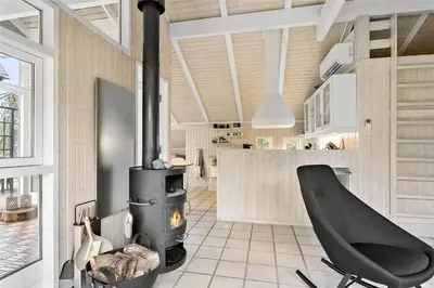 a living room with a fireplace and a chair at 435-Vestervig-Sivsangervej-32 in Vestervig