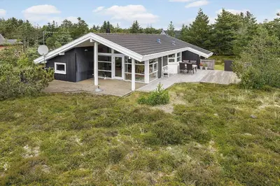 a small black house with a deck in a field at 248-Thisted-Molgaardsvej-28 in Thisted