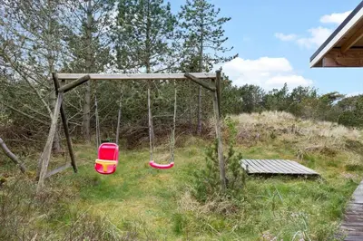 a swing set in a field with a bench at 849-Thisted-Havtornvej-6 in Thisted