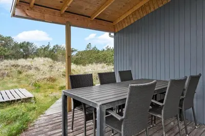 a wooden table and chairs on a deck with a view at 849-Thisted-Havtornvej-6 in Thisted