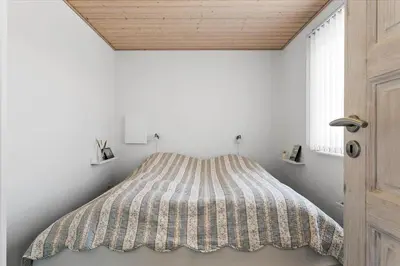 a bed in a white room with a striped comforter at 497-Thisted-Nordsovej-26 in Thisted
