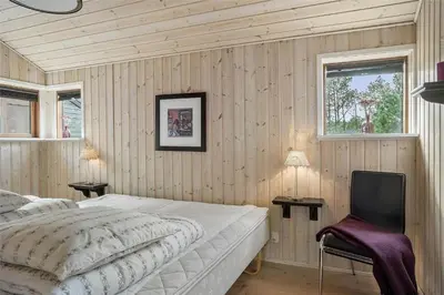 a bedroom with a bed and a chair and a window at 748-Thisted-Blamunkevej-65 in Thisted