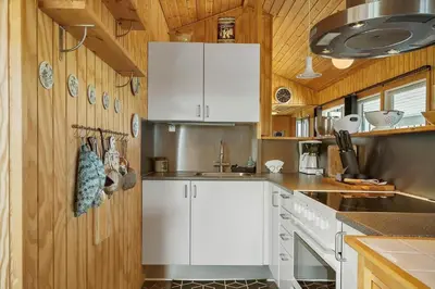 a kitchen with white cabinets and wooden walls at 306-Vestervig-Klitvej-6 in Vestervig