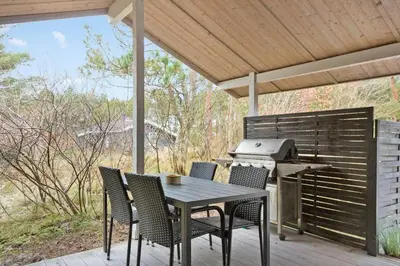 a table and chairs on a deck with a grill at 851-Thisted-Blabaervej-1 in Thisted