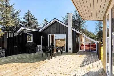 a black house with a deck with a table and chairs at 1312-Thisted-Kristinesvej-38 in Thisted
