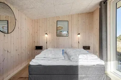 a large bed in a room with wood paneling at 1312-Thisted-Kristinesvej-38 in Thisted