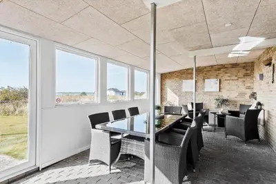 a dining room with a table and chairs and windows at 600-Vestervig-Krik-Strandvej-100 in Vestervig