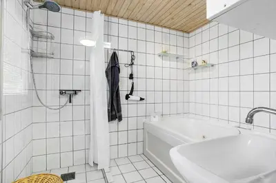 a white tiled bathroom with a tub and a sink at 317-Thisted-Molgaardsvej-65 in Thisted