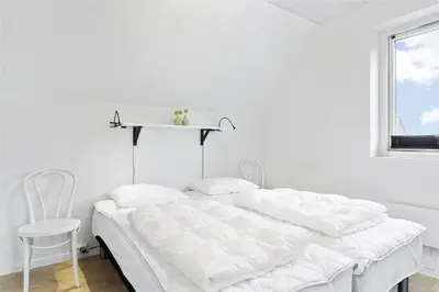 a white bedroom with a bed and a chair at 793-Thisted-Havstokken-24-1 in Thisted