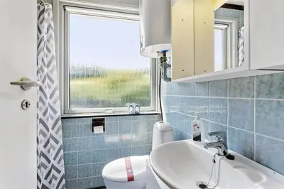 a bathroom with a sink and a toilet and a window at 982-Thisted-Clemmessti-16 in Torsted