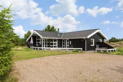 a black house with a bench in front of it at 988-Thisted-Spanggardsvej-67 in Torsted