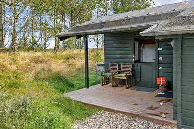 a green cabin with two chairs and a table on a deck at 1307-Bedsted-Thy-Nordre-Redningsvej-4 in Bedsted Thy