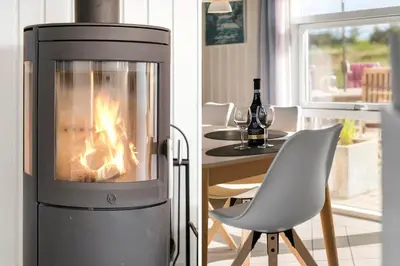 a fireplace in a living room with a chair and a table at 1039-Thisted-Niels-Vognmands-Vej-19 in Torsted