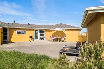 a yellow house with a patio and a table at 1039-Thisted-Niels-Vognmands-Vej-19 in Torsted