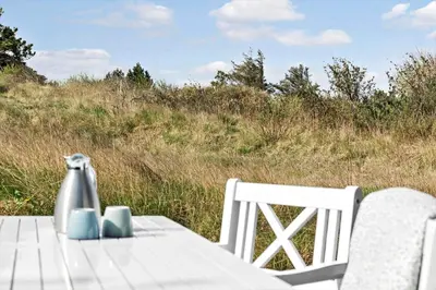 a table with two chairs and a vase on it at 192-Snedsted-Sarasvej-12 in Snedsted
