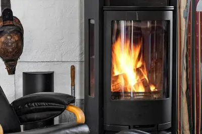 a fireplace with a fire in it next to a chair at 219-Thisted-Fiskervej-16 in Thisted