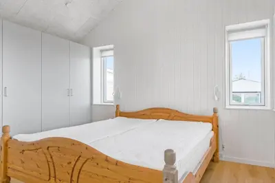 a bedroom with a wooden bed and two windows at 167-Thisted-Vesterhavsgade-158 in Thisted