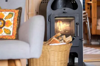 a fireplace in a living room with a chair and a basket at 916-Thisted-Spanggardsvej-59 in Torsted