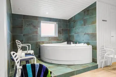 a bathroom with a tub and a sink and chairs at 1028-Thisted-Tingbakken-28 in Torsted