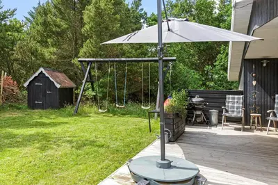 a patio with an umbrella and a swing and a grill at 1028-Thisted-Tingbakken-28 in Torsted