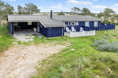 a blue house with a white fence in a field at 596-Thisted-Blabaervej-15 in Thisted