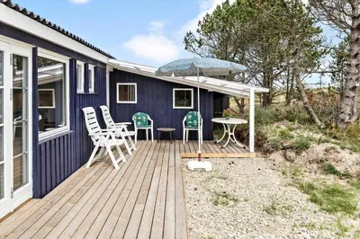 a blue house with a deck with a table and chairs at 596-Thisted-Blabaervej-15 in Thisted