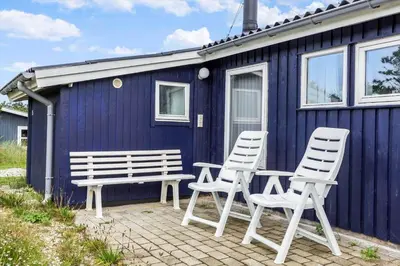 a couple of chairs and a bench in front of a blue house at 596-Thisted-Blabaervej-15 in Thisted