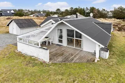 a small white house with a deck in a field at 588-Thisted-Grarisvej-9 in Thisted