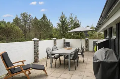 a patio with a table and chairs and an umbrella at 118-Vestervig-Sivsangervej-18 in Vestervig