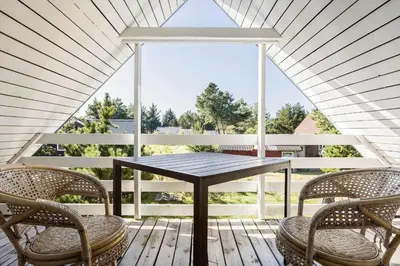 a table and chairs on a porch with a large window at 420-Vestervig-Kanalvej-4 in Vestervig