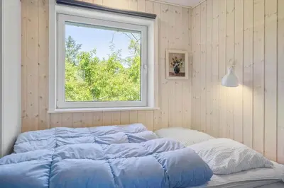 a bed with blue sheets in a room with a window at 420-Vestervig-Kanalvej-4 in Vestervig